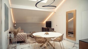 Un espace repas moderne avec une table ronde, des chaises dorées et un canapé capitonné.
