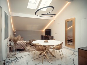 Un espace repas moderne avec une table ronde, des chaises dorées et un canapé capitonné.
