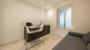 A compact room with a kitchenette, a dining area with two chairs, a sofa, and a window with blinds. - Apartment 'App 202 Palazzo Cavour' with Mountain View, Wi-Fi and Air Conditioning (Bolzano)