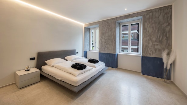 A modern bedroom with a bed, nightstand, and a window with a view. - Apartment 'App 202 Palazzo Cavour' with Mountain View, Wi-Fi and Air Conditioning (Bolzano)