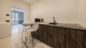 A modern kitchen with a wooden island, white bar stools, a black faucet, and a coffee machine. - Apartment 'App 202 Palazzo Cavour' with Mountain View, Wi-Fi and Air Conditioning (Bolzano)