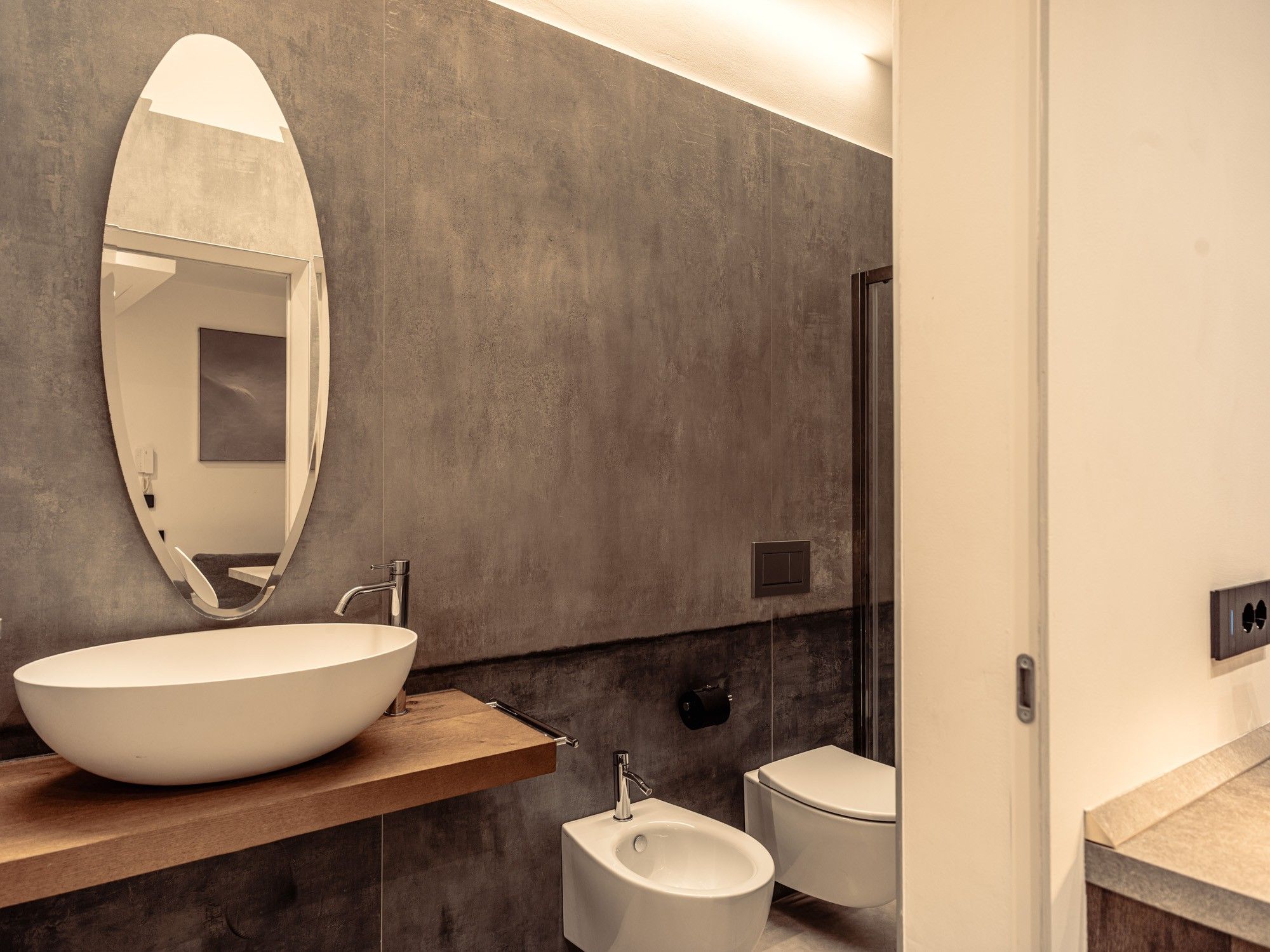 A modern bathroom with a large oval sink, a rectangular mirror, and a toilet.