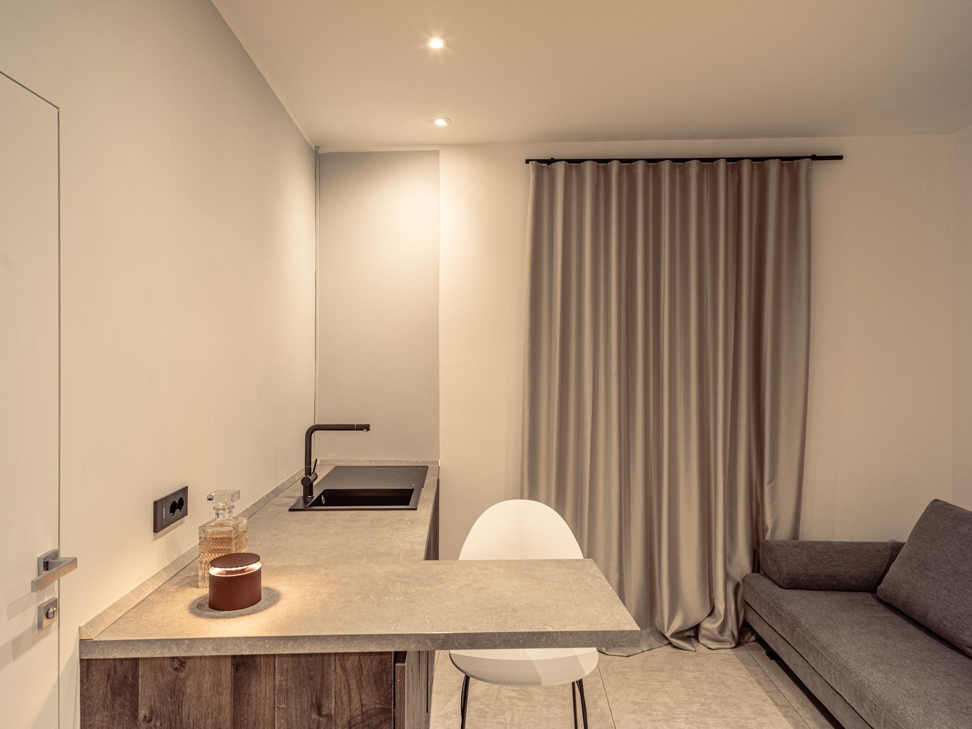Ein modernes, kompaktes Wohnzimmer mit Küchenzeile, einer Couch und einem Essbereich.