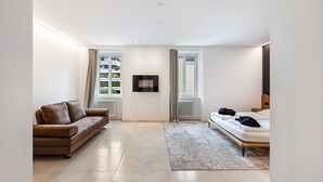 Un dormitorio moderno con sofá, cama, radiador y ventana.