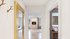 Un pasillo con un espejo, una chimenea y vistas a otra habitación.