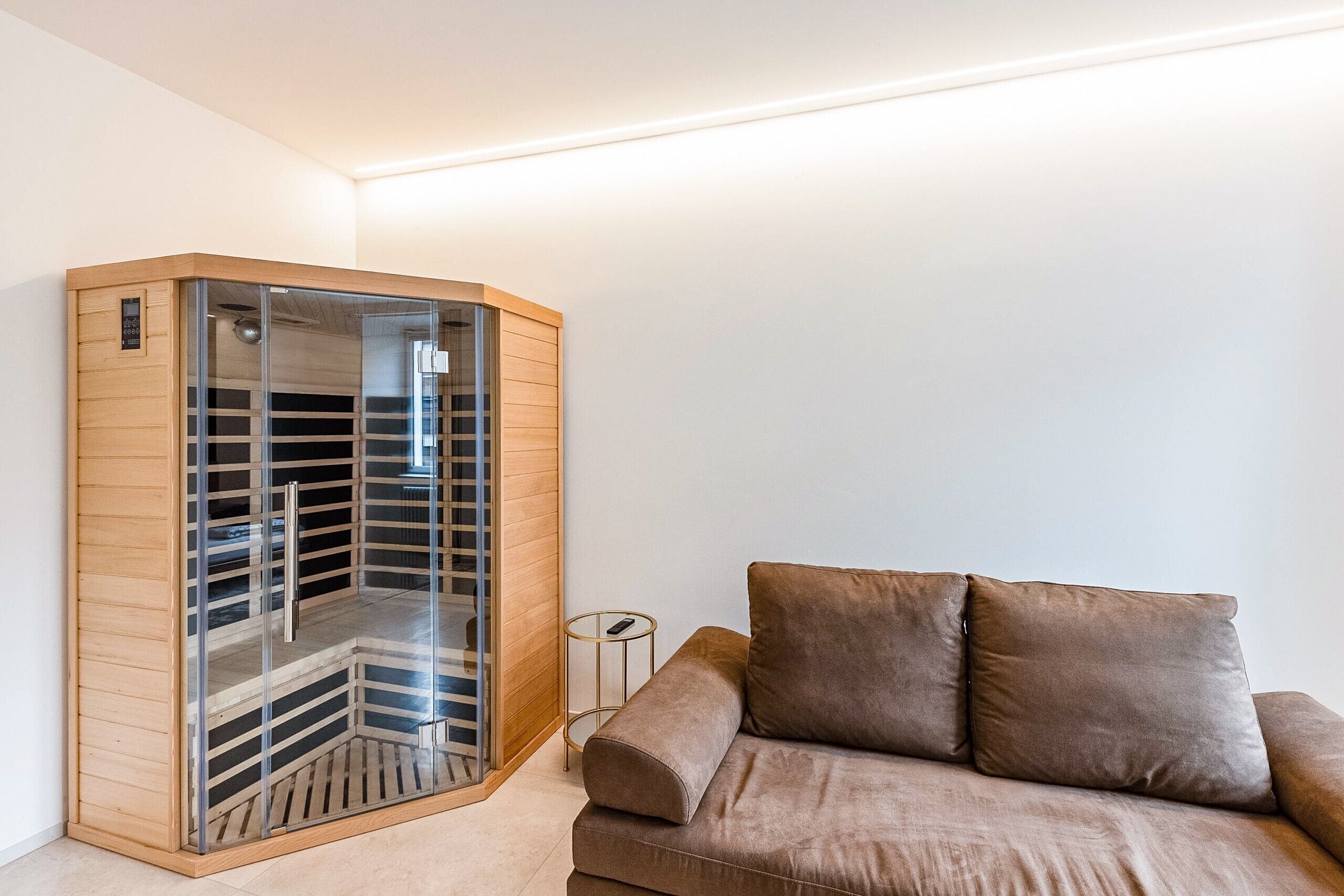 A corner room with a built-in wardrobe, a small round table, and a brown sofa.