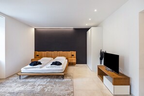 A modern bedroom with a bed, bedside tables, a TV, and a large window.