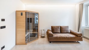 Un salón moderno con un sofá de cuero marrón, un mueble de madera con puertas de cristal y una pequeña mesa redonda.