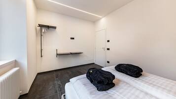 Een moderne hotelkamer met een bed, een radiator, een handdoekrek en een deur.