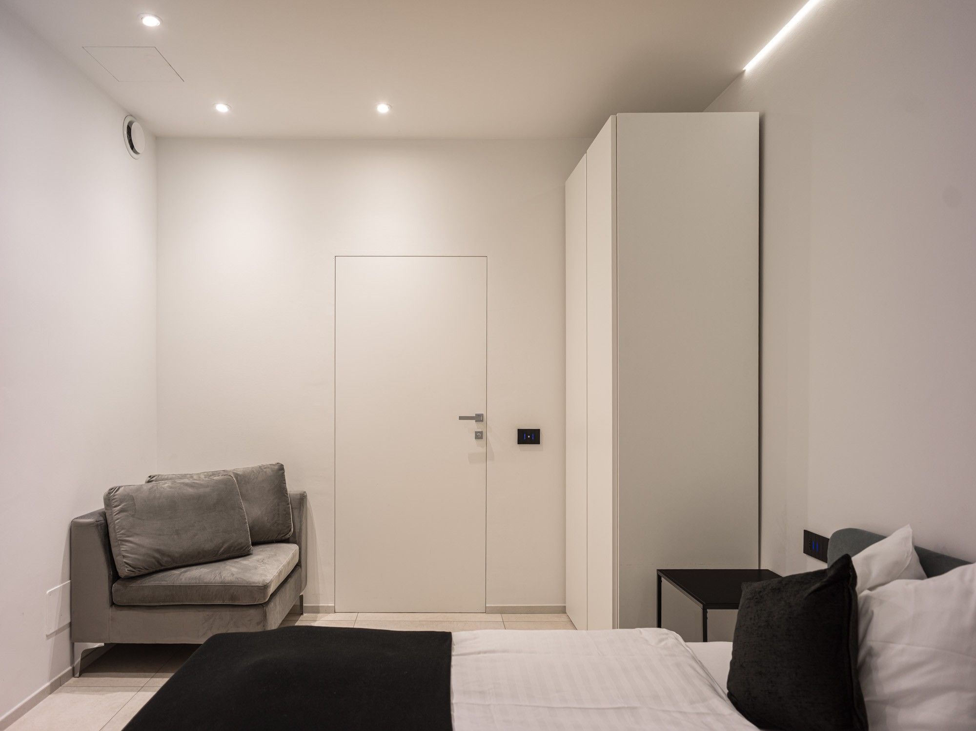 A modern bedroom with a bed, a sofa, and a wardrobe.