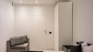 A modern bedroom with a bed, a sofa, and a wardrobe.