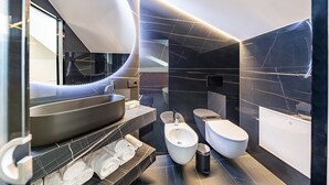 Een moderne badkamer met een toilet, wastafel en douchetoilet.