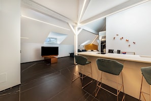 A modern kitchen with a bar area, dark flooring, and a large window.