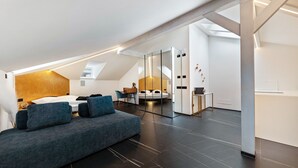 Een moderne loft slaapkamer met een slaapbank, een bed, een bureau en een inbouwkast met spiegel.