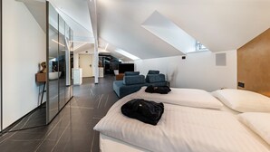 Een moderne hotelkamer met dakraam, een groot bed, een zithoek en een glazen scheiding.