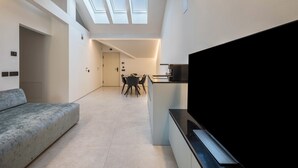 Un intérieur moderne comprenant un canapé, un coin repas et un téléviseur.