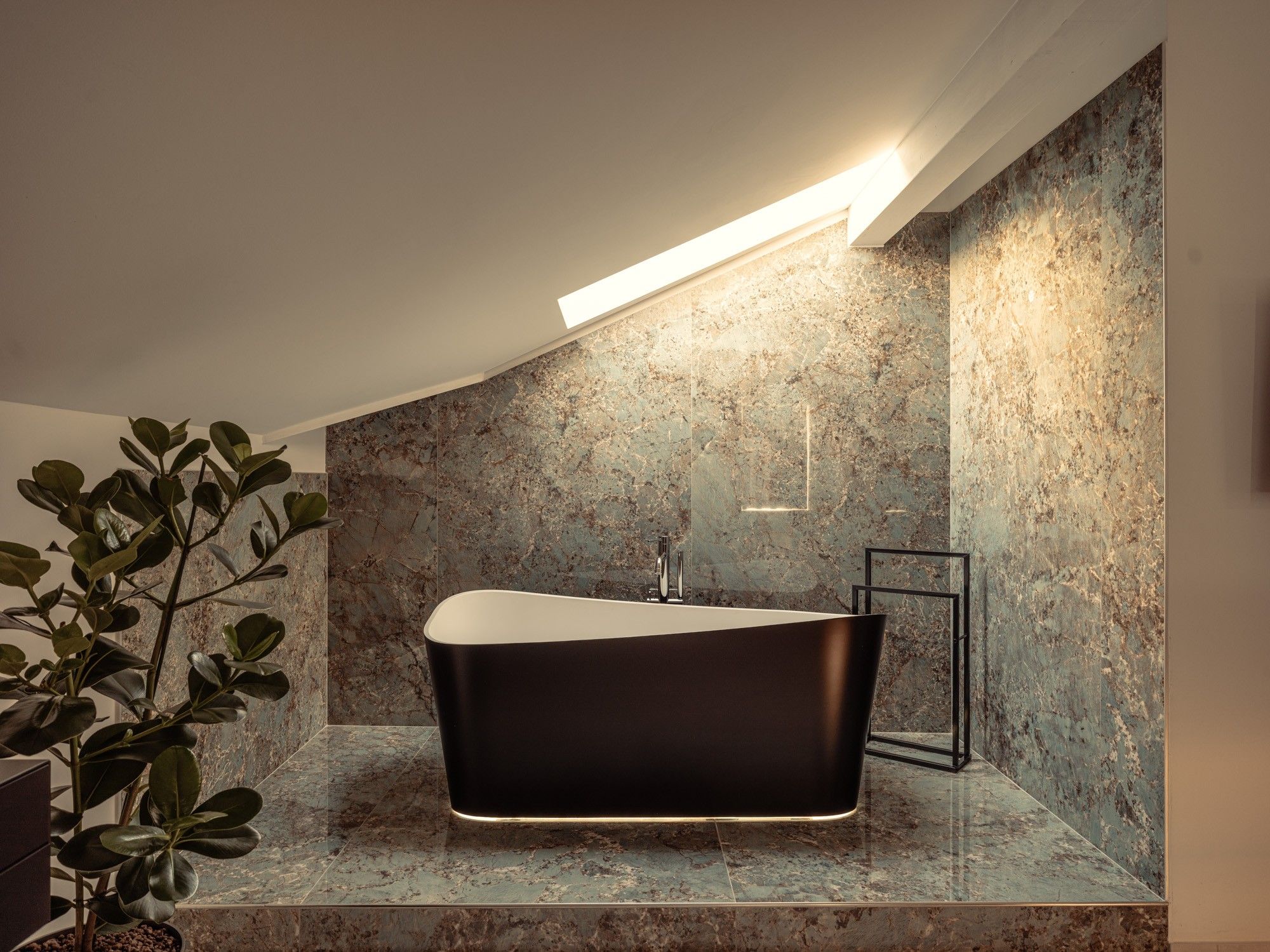 Un bagno moderno con una vasca freestanding, una parete in marmo e un lucernario.