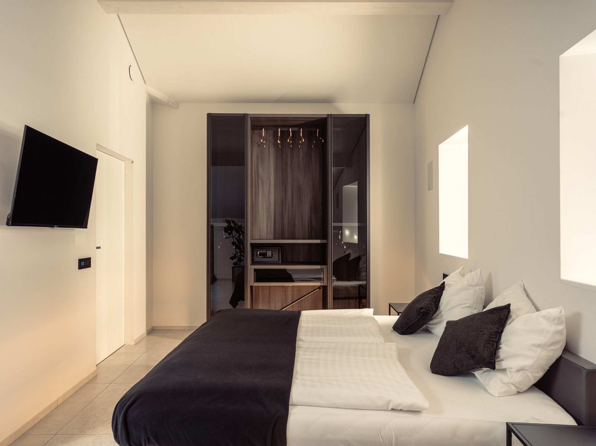 Una camera da letto moderna con un letto, una TV a muro e una cabina armadio.