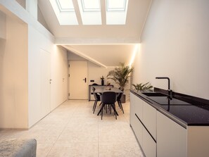 Una cucina moderna con zona pranzo, lucernari e vista sull'ambiente adiacente.
