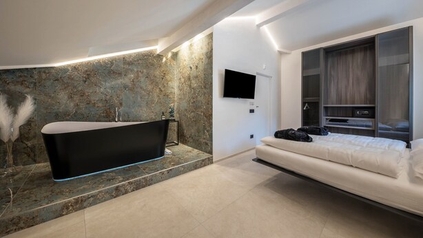 Une salle de bain moderne avec une baignoire sur pieds, un grand miroir et un téléviseur à écran plat fixé au mur.