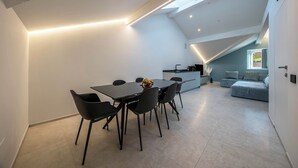 Un intérieur moderne comprenant un coin repas, une cuisine et un espace de vie, agrémenté de fenêtres de toit et d’un plancher de couleur claire.