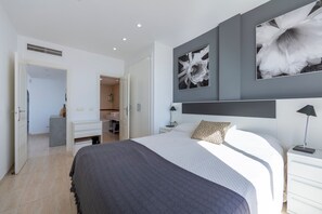 Een moderne slaapkamer met een groot bed, een bureau en een kledingkast.