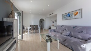Un saló modern amb una taula de centre de vidre, un sofà i una zona de menjador amb cadires.