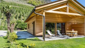 Une cabane en bois dotée d’un patio couvert, d’une allée en gravier et d’un jardin luxuriant.