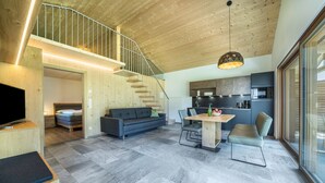Un intérieur moderne comprenant un escalier, un coin repas, un canapé et une cuisine.
