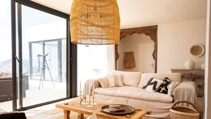 Ein Wohnzimmer mit einer Couch, einem Couchtisch, einem Korbwäscheschrank und einem großen Fenster.