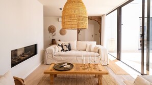 Ein modernes Wohnzimmer mit einem weißen Sofa, einem Holztisch und einer großen, gewebten Pendelleuchte.