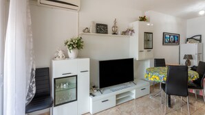 A modern living room with a flat-screen TV, white cabinetry, a dining area with a table and chairs, and a mounted air conditioner. - Beautiful Vacation Hom "Mtsrat8 "e with Air Conditioning & Terrace (Torrevieja)