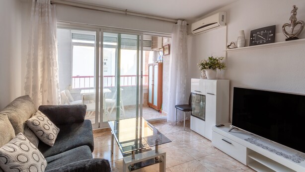 A living room with a sofa, a glass coffee table, a flat-screen TV, a fireplace, and a balcony with a sliding door. - Beautiful Vacation Hom "Mtsrat8 "e with Air Conditioning & Terrace (Torrevieja)