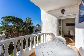 A balcony with a white table and chairs, a view of trees and buildings, and a door leading to an interior room. - "5 bedroom Villa private Pool and Garden" close to the Sea with Pool & Wi-Fi (Orihuela)