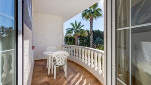 A balcony with a white railing, a table, and two chairs.