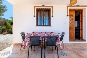 A patio with a table and chairs, a window with decorative bars, and a door leading inside.