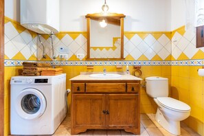 Un bagno dotato di lavatrice, mobili in legno, un lavandino e un water.