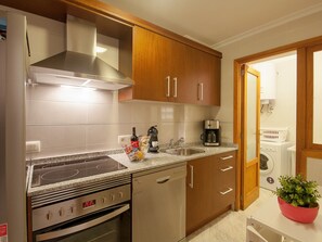 A kitchen with a stove, oven, coffee maker, and a sink.