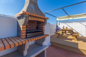 Un barbecue en briques installé à l’extérieur, avec une table et des chaises à proximité.