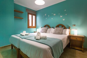 Quarto com duas camas, uma janela, uma mesinha de cabeceira e adesivos de borboletas na parede.