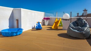 A rooftop deck with a slide, a blue plastic tub, a scooter, and a bean bag chair. - Obelisc-3--------------------- (Can Picafort)