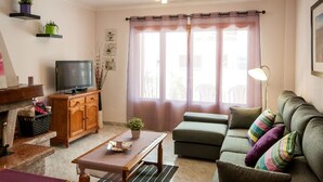 A living room with a television, sofa, table, and decorative plants. - Obelisc-3--------------------- (Can Picafort)
