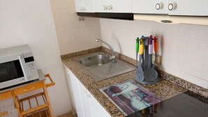 A kitchen with a microwave, sink, and a dish rack.