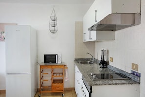 A compact kitchen with a microwave, sink, and stainless steel range hood.