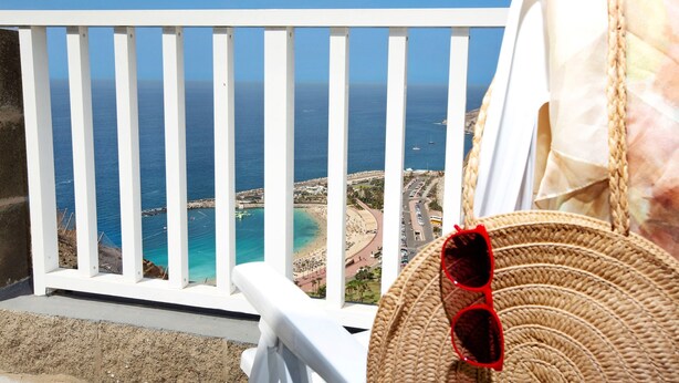 Un balcon avec vue sur la mer, un panier en osier et une balustrade blanche.