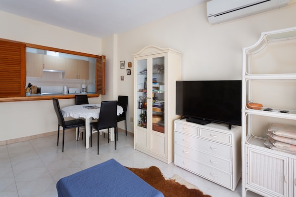 Une pièce comprenant une table à manger, des chaises, un téléviseur, une armoire et un lit.