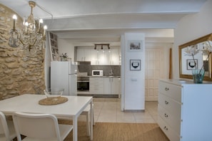 Eine moderne Küche mit weißen Schränken, einer Steinwand und einer Chandelier.