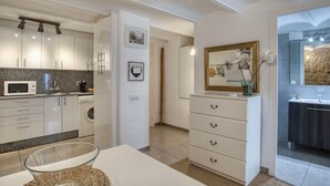 A modern kitchen with white cabinetry, a microwave, and a washing machine.