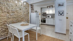 A modern kitchen with white cabinets, a stone wall, and a dining area with a white table and chairs.