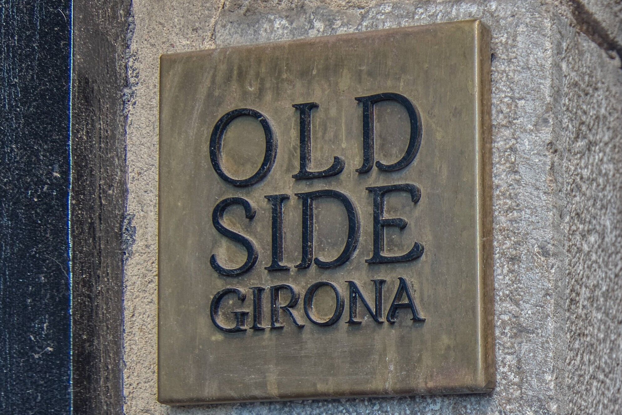Een bord met de tekst 'OLD SIDE GIRONA' op een stenen muur.